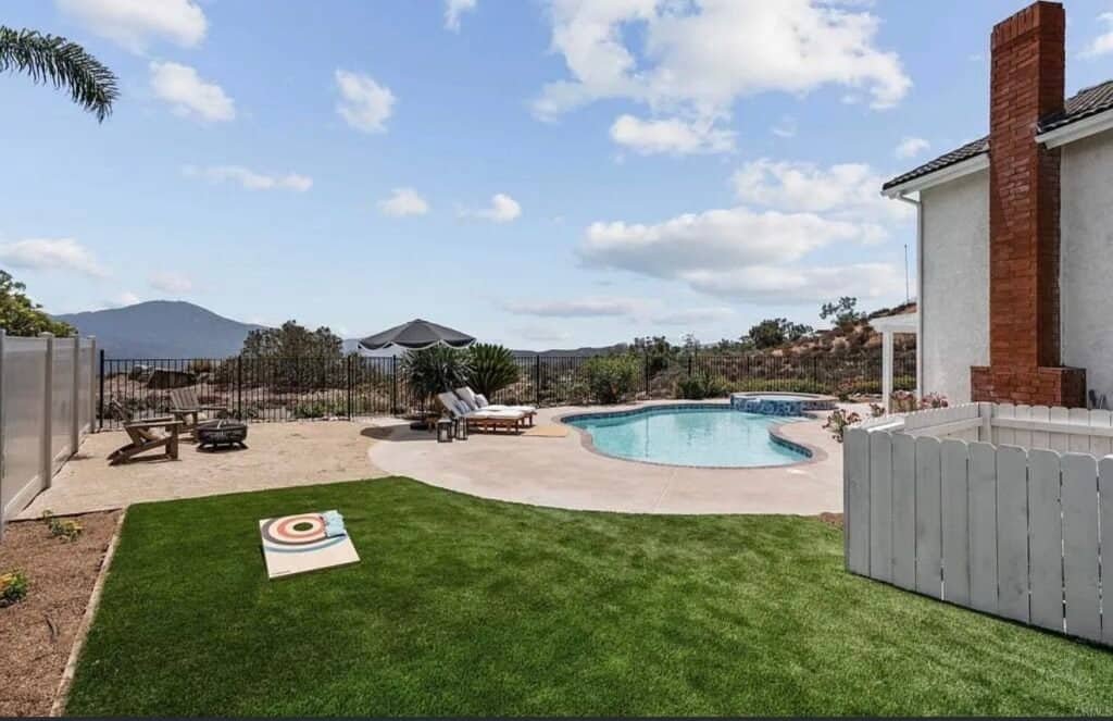 Beautiful backyard with pool, lawn, and scenic mountain view under blue sky.