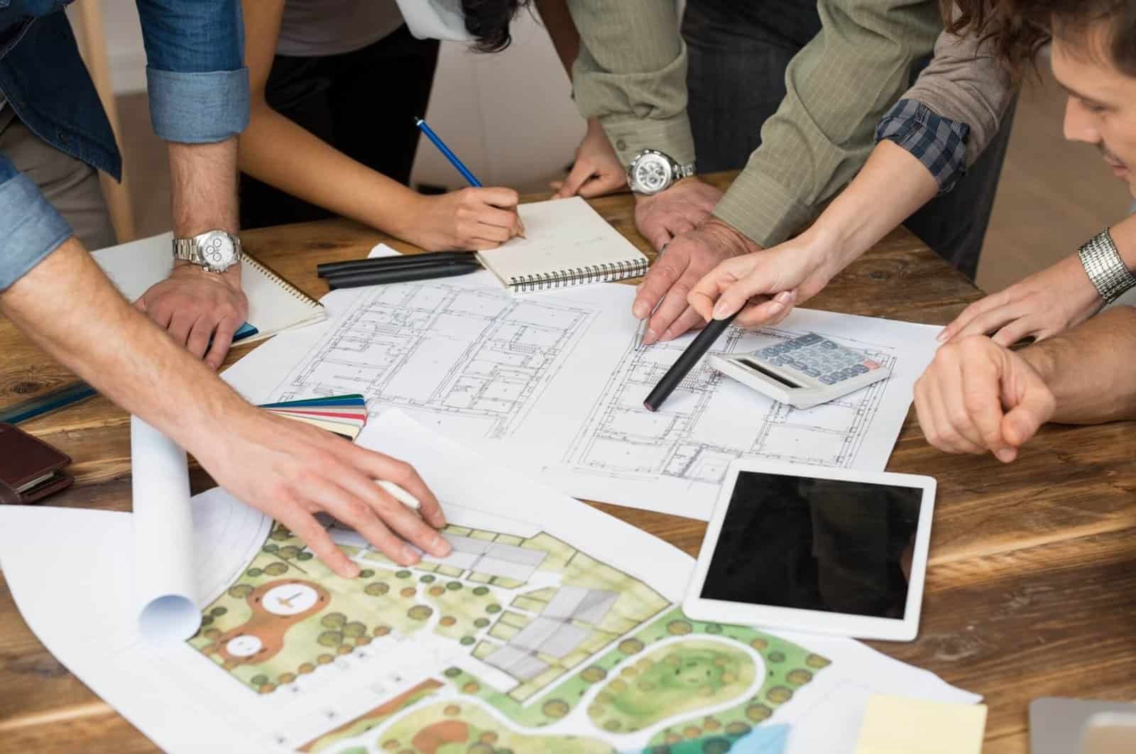 Team collaborating on landscape design plans with tools and blueprints.